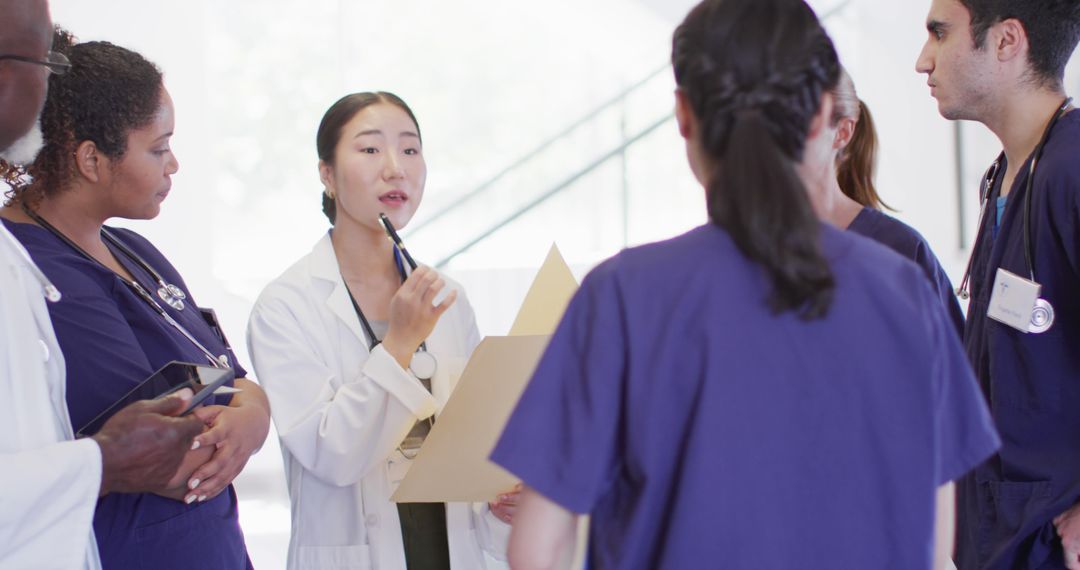 Image of asian female doctor with file talking to diverse medical colleagues in hospital corridor - Free Images, Stock Photos and Pictures on Pikwizard.com