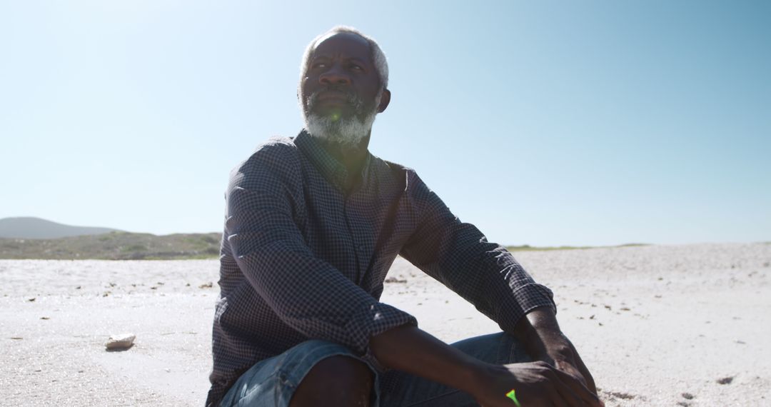 Senior Man Reflecting at Tranquil Beach on Sunny Day - Free Images, Stock Photos and Pictures on Pikwizard.com