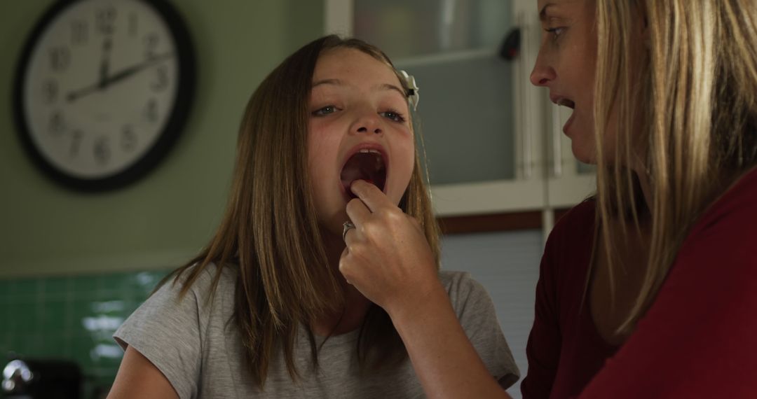 Mother Examining Young Daughter's Throat in Kitchen - Free Images, Stock Photos and Pictures on Pikwizard.com