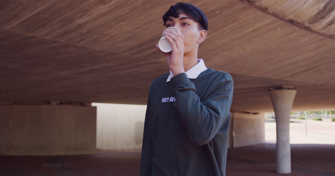 Young Man Drinking Coffee Under Urban Bridge - Free Images, Stock Photos and Pictures on Pikwizard.com