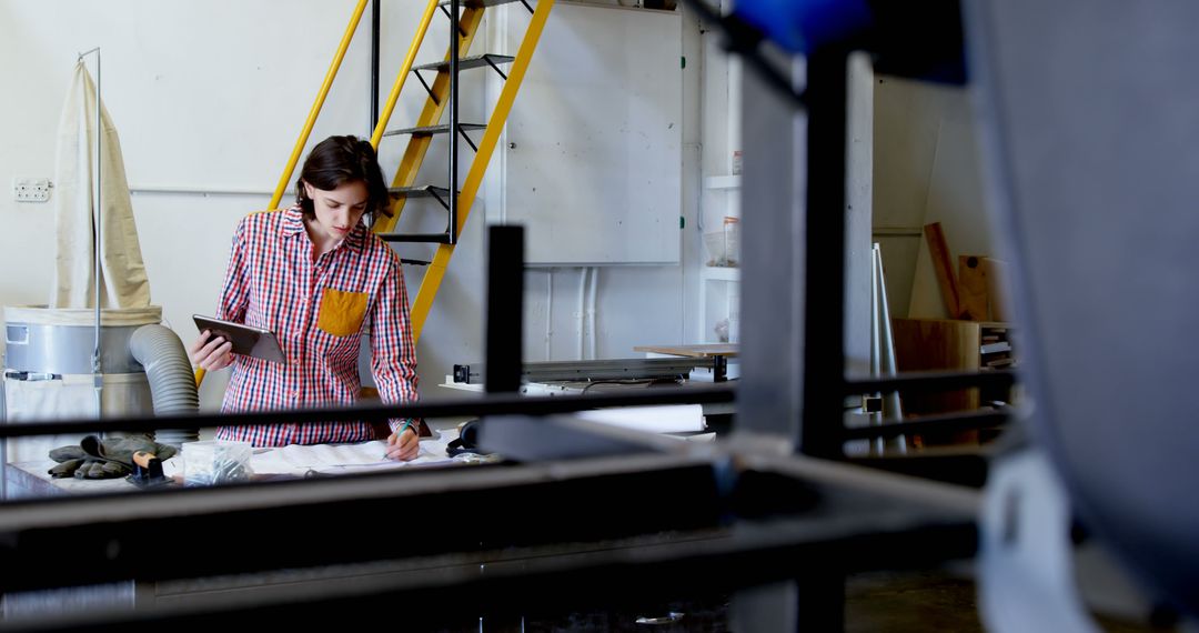 Female Engineer Reviewing Blueprints in Industrial Workshop - Free Images, Stock Photos and Pictures on Pikwizard.com