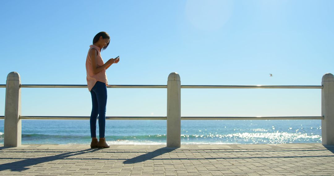 Young Woman Using Smartphone by Ocean on Sunny Day - Free Images, Stock Photos and Pictures on Pikwizard.com