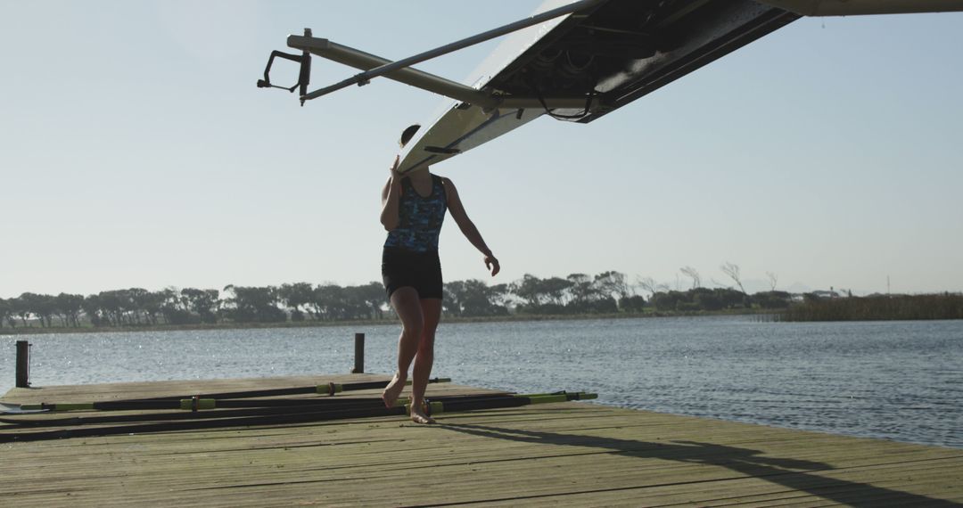 Athlete Carrying Rowing Shell on Dock with Lake Background - Free Images, Stock Photos and Pictures on Pikwizard.com