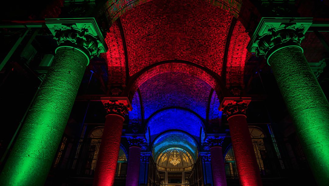 RGB Illuminating Historic Arched Entrance with Columns and Vaulted Ceiling at Night