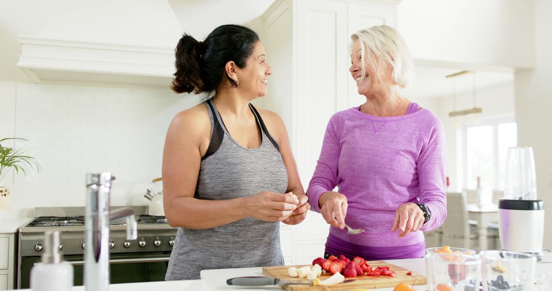 Middle-aged women preparing fruit in modern kitchen, enjoying conversation - Free Images, Stock Photos and Pictures on Pikwizard.com