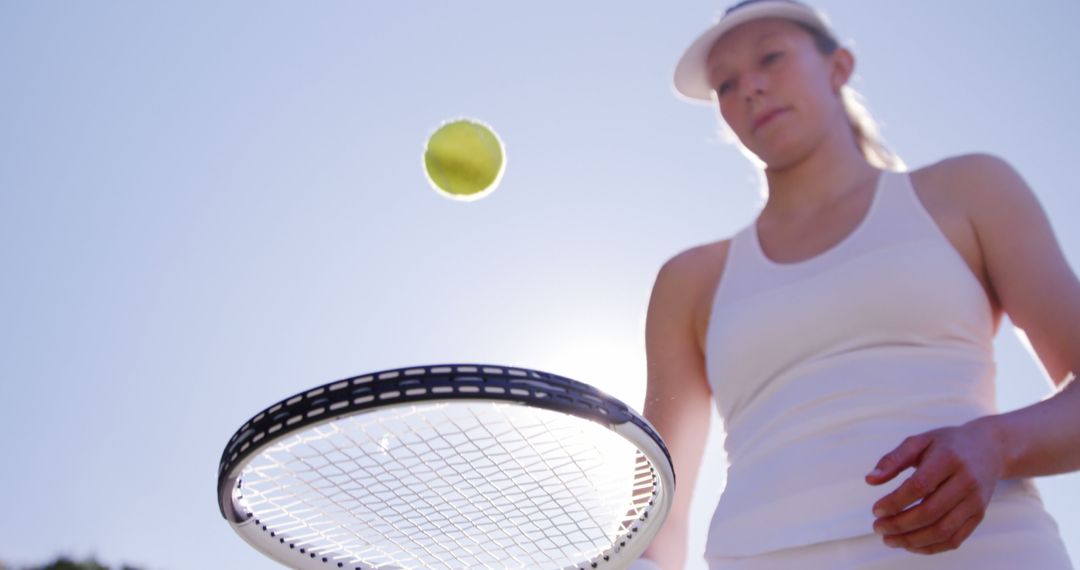 Female Tennis Player Balancing Tennis Ball with Racket on Sunny Day - Free Images, Stock Photos and Pictures on Pikwizard.com