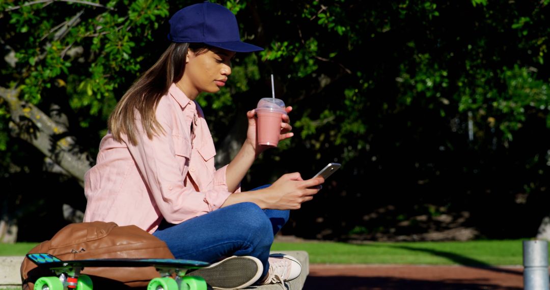 Young woman relaxing with smoothie and smartphone in park - Free Images, Stock Photos and Pictures on Pikwizard.com