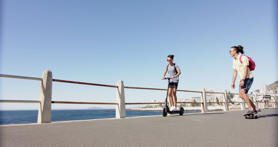 Two Friends Enjoying Ride on Electric Scooter and Skateboard by Seaside - Free Images, Stock Photos and Pictures on Pikwizard.com