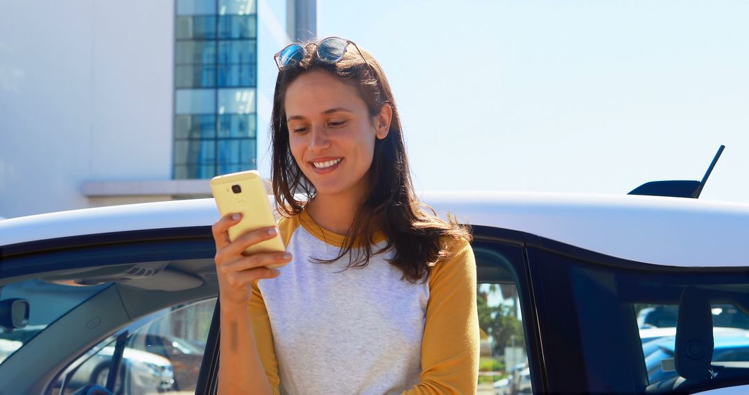 Young Woman Smiling Using Smartphone near Car Outdoors - Free Images, Stock Photos and Pictures on Pikwizard.com