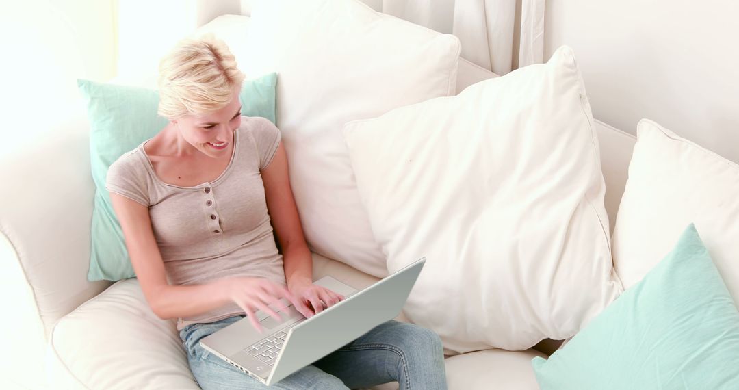 Smiling Woman Working on Laptop While Sitting on Comfortable Couch at Home - Free Images, Stock Photos and Pictures on Pikwizard.com