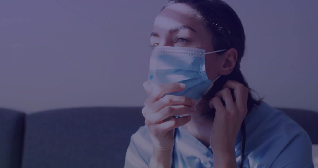 Healthcare Worker Relaxing in Lounge Adjusting Surgical Mask