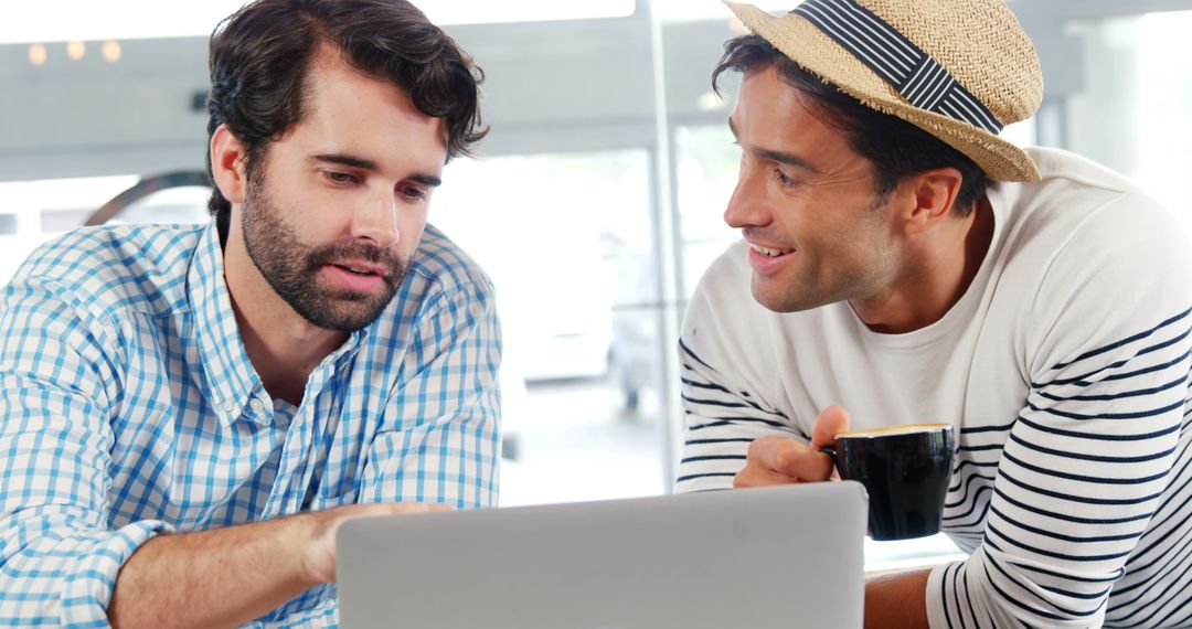 Two Men Collaborating on Laptop with Coffee in Bright Office - Free Images, Stock Photos and Pictures on Pikwizard.com