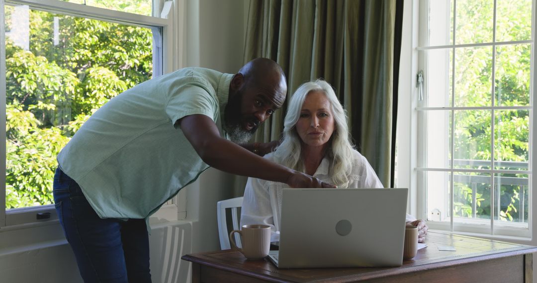Diverse Couple Collaborating on Laptop at Home for Work Discussion