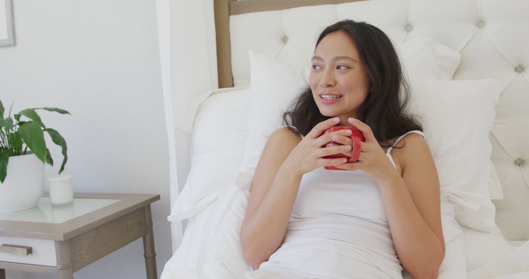 Young Woman Relaxing in Bed with Hot Drink in Cozy Modern Bedroom - Free Images, Stock Photos and Pictures on Pikwizard.com