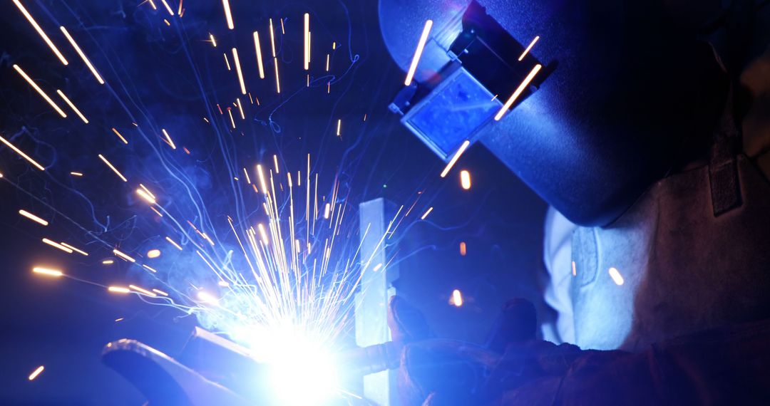 Welder Wearing Protective Gear in Workshop with Sparking Flames - Free Images, Stock Photos and Pictures on Pikwizard.com