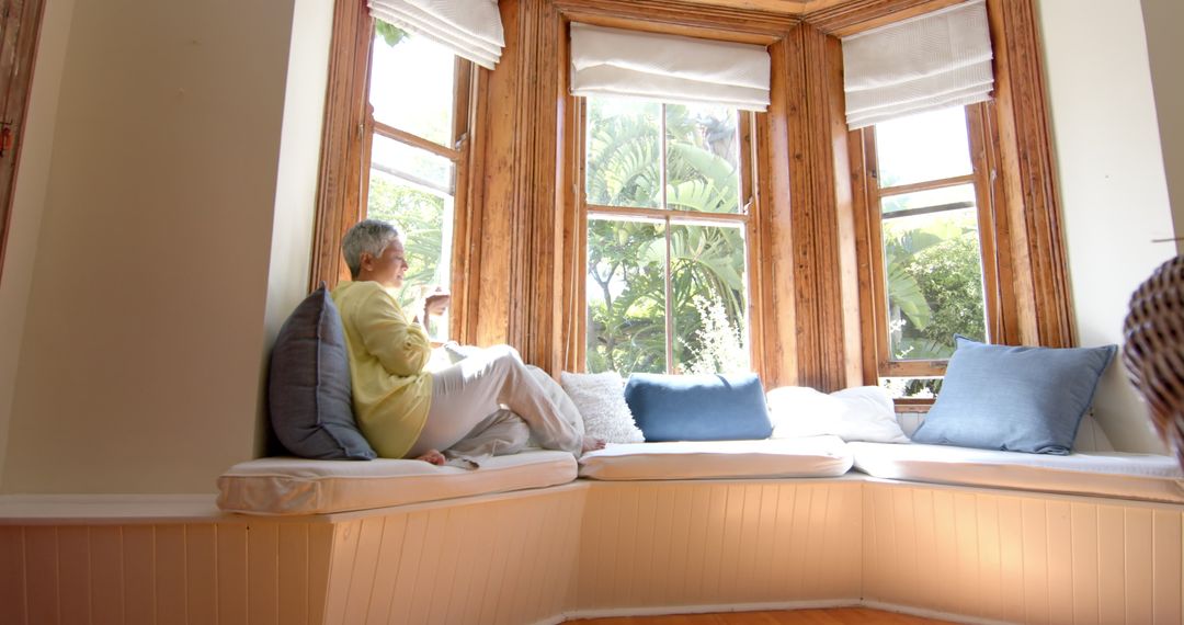 Senior woman relaxing with tea on sunlit window seat