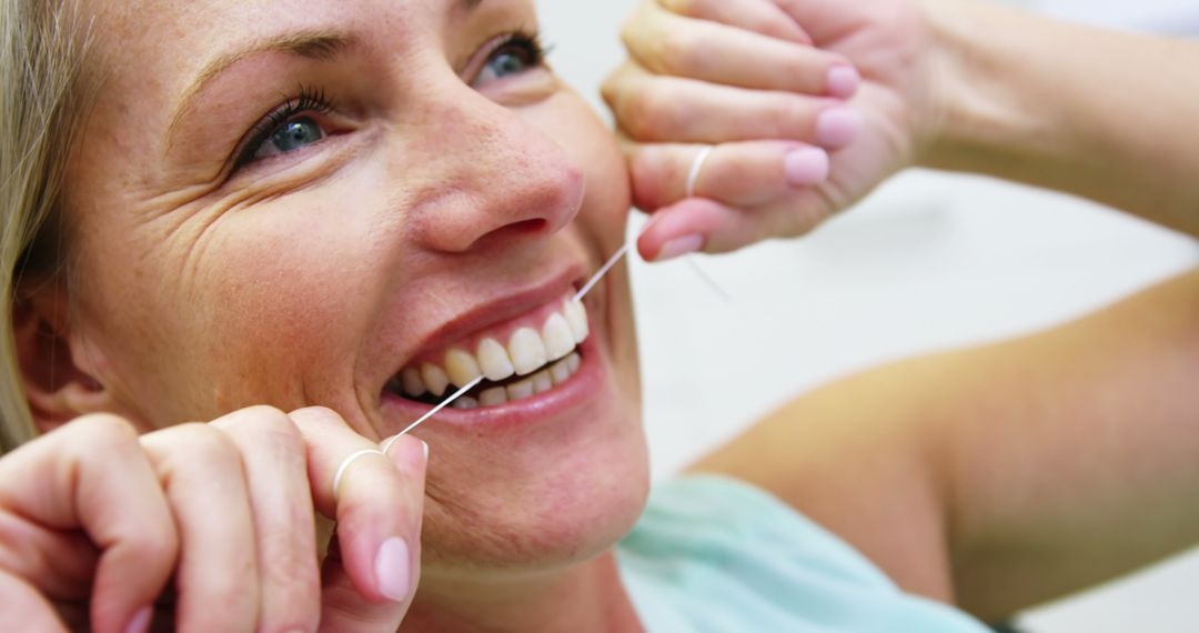 Smiling Woman Flossing Teeth for Dental Hygiene - Free Images, Stock Photos and Pictures on Pikwizard.com