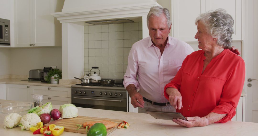 Happy caucasian senior couple in kitchen using tablet for recipe before preparing meal - Free Images, Stock Photos and Pictures on Pikwizard.com