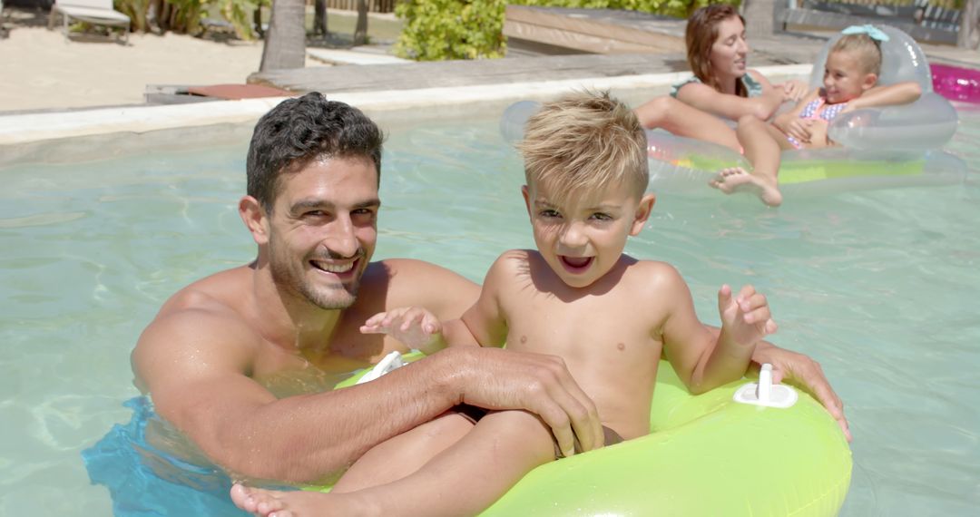 Family Enjoying Vacation Swimming in Pool with Inflatable Rings on Sunny Day - Free Images, Stock Photos and Pictures on Pikwizard.com