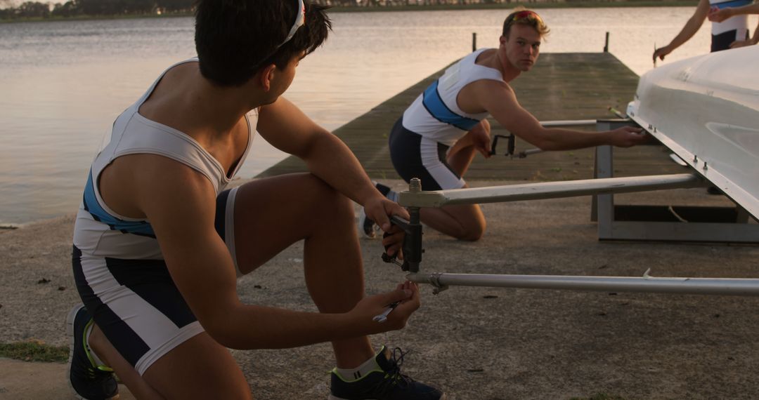 Young Rowers Rigging Boat at Sunset by Lake - Free Images, Stock Photos and Pictures on Pikwizard.com