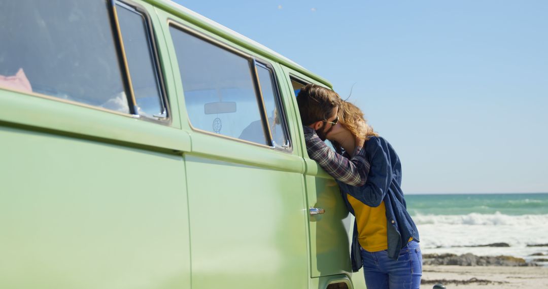 Woman resting her head on vintage camper van by beach - Free Images, Stock Photos and Pictures on Pikwizard.com