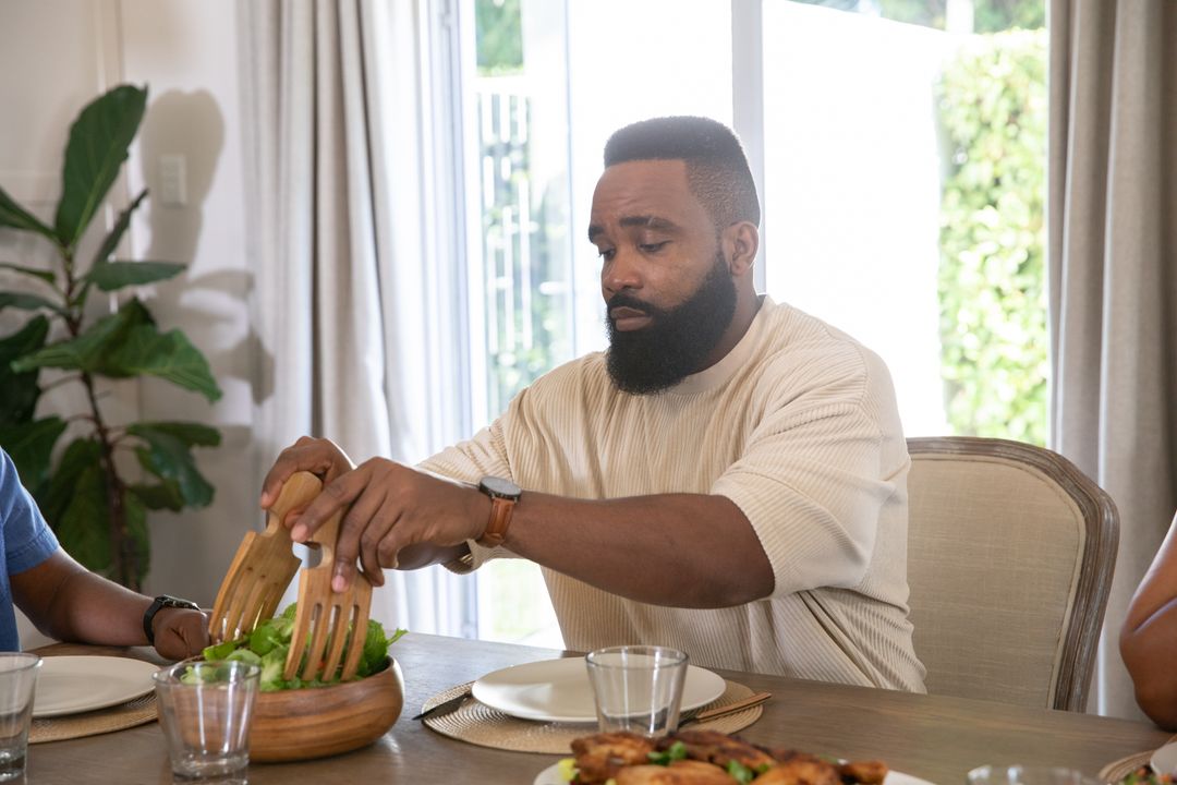 Man Tossing Fresh Salad at Rustic Dining Table