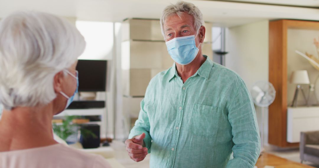 Senior Couple Wearing Masks Greeting with Elbows at Home