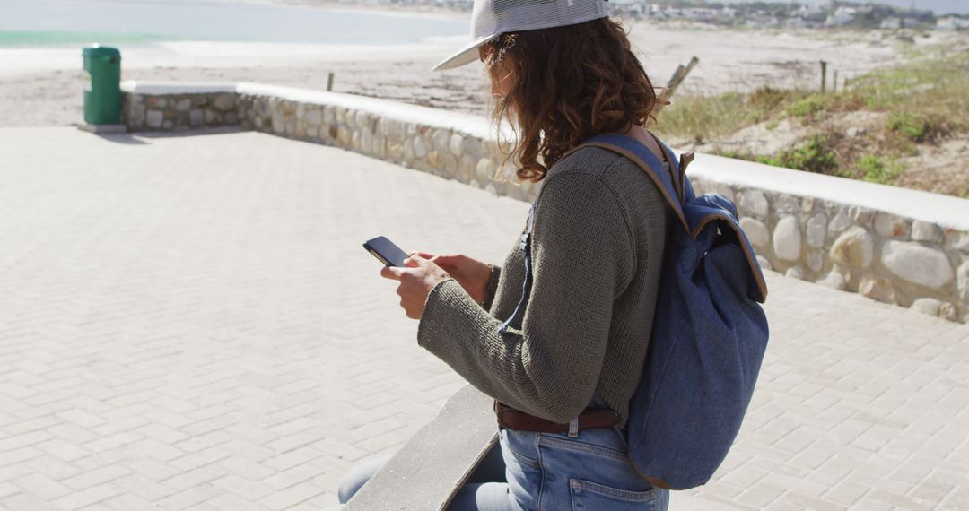 Girl with Backpack and Skateboard Using Smartphone at Beach - Free Images, Stock Photos and Pictures on Pikwizard.com