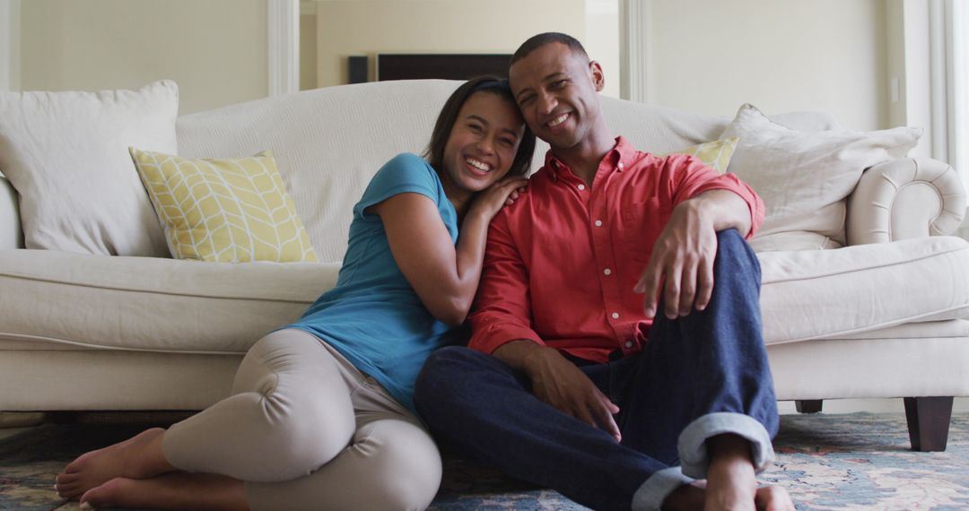 Happy Couple Relaxing on Floor Embracing and Smiling at Camera