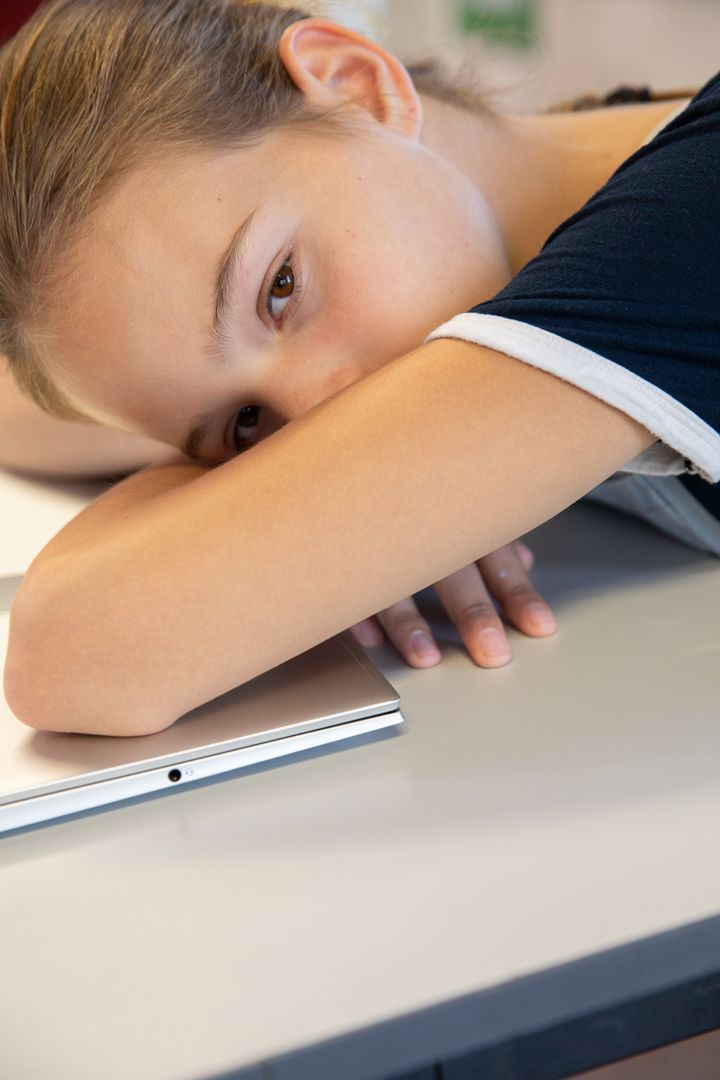 Adolescent Girl Relaxing on School Desk with Laptop