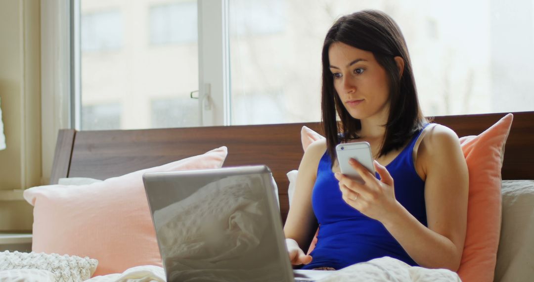 Woman Working from Home Using Laptop and Smartphone in Bed - Free Images, Stock Photos and Pictures on Pikwizard.com