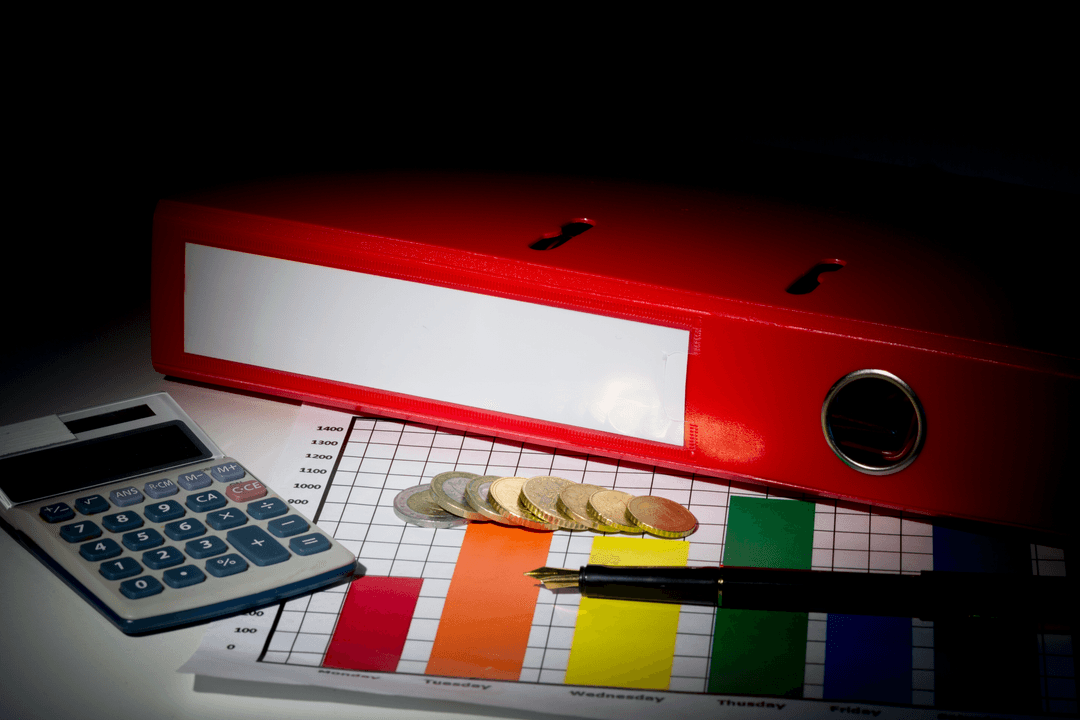 Transparent Red Binder with Calculator Coins on Desk