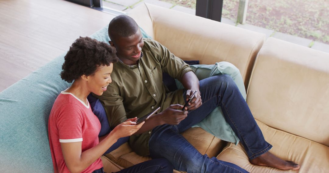 Image of happy african american couple sitting on sofa and using tablet - Free Images, Stock Photos and Pictures on Pikwizard.com