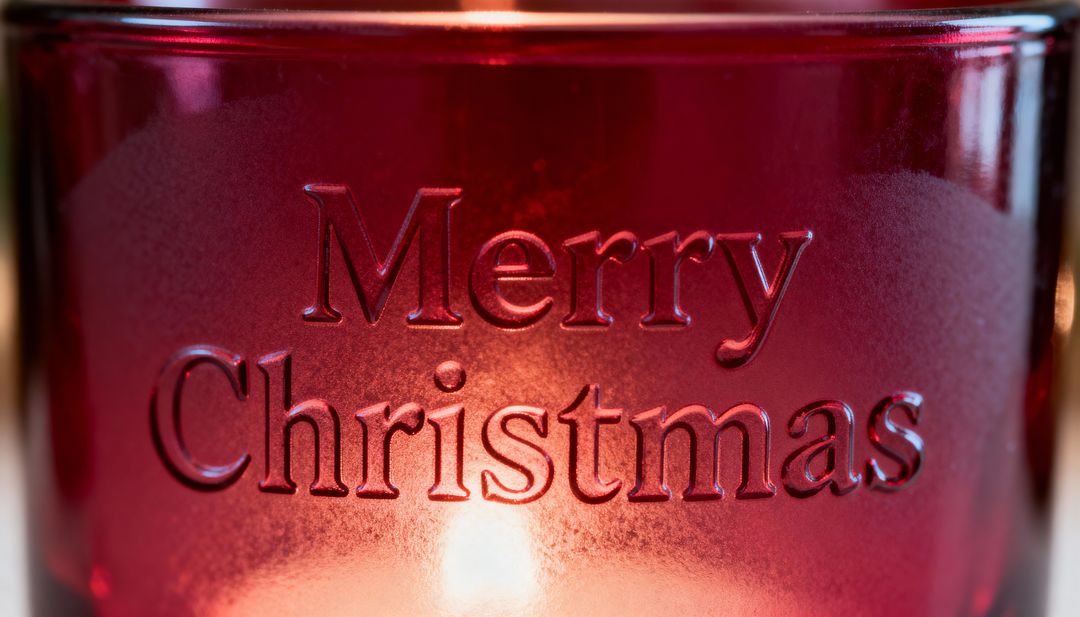 Glowing red frosted candle holder embossed Merry Christmas with warm candlelight glow