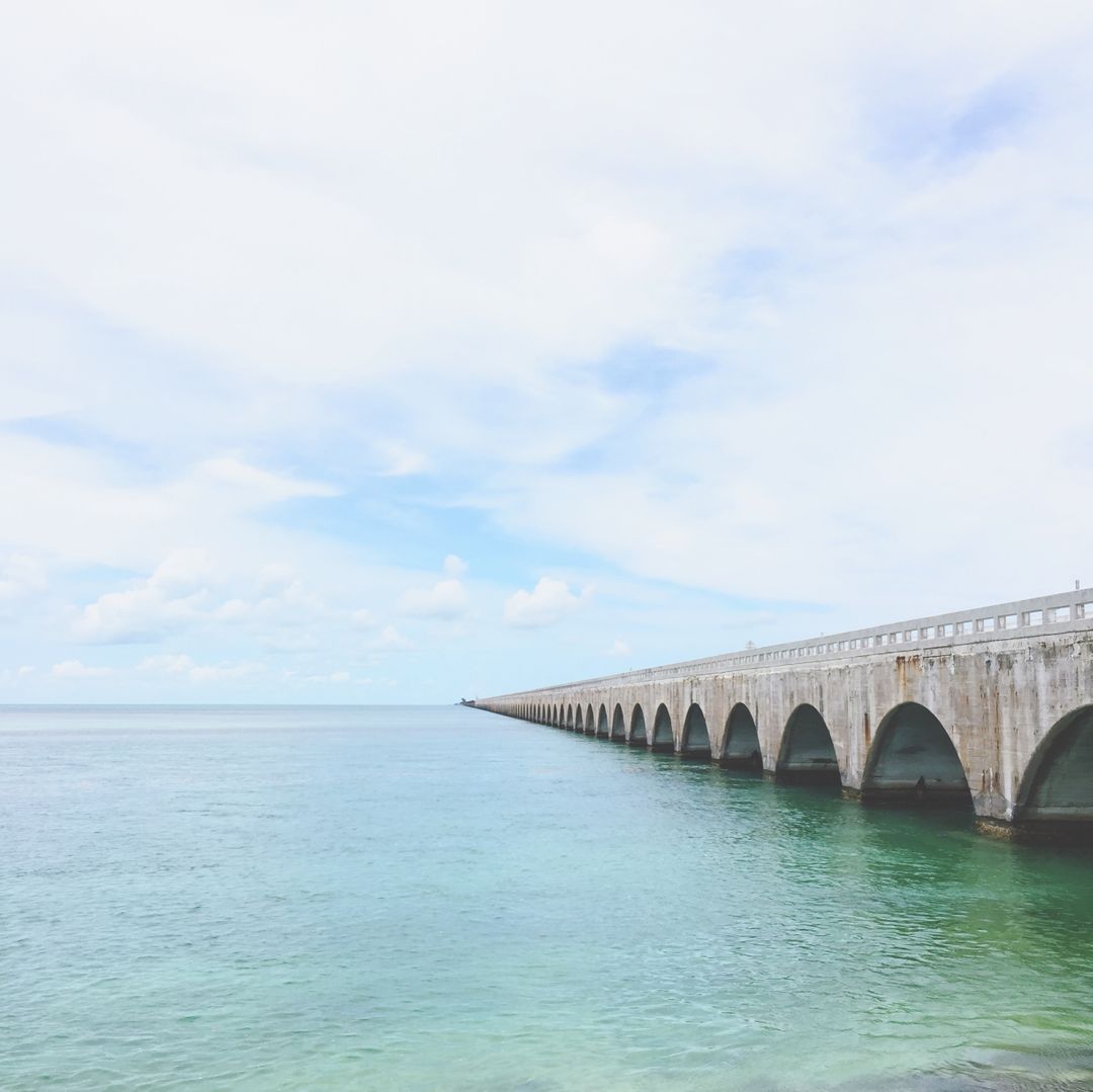 Scenic Ocean View with Historic Bridge Extending Over Clear Water - Free Images, Stock Photos and Pictures on Pikwizard.com