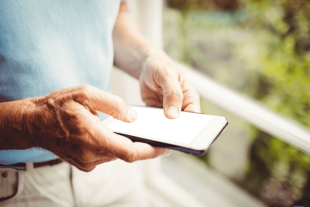 Senior Man Holding Smartphone Near Window with Transparent Screen