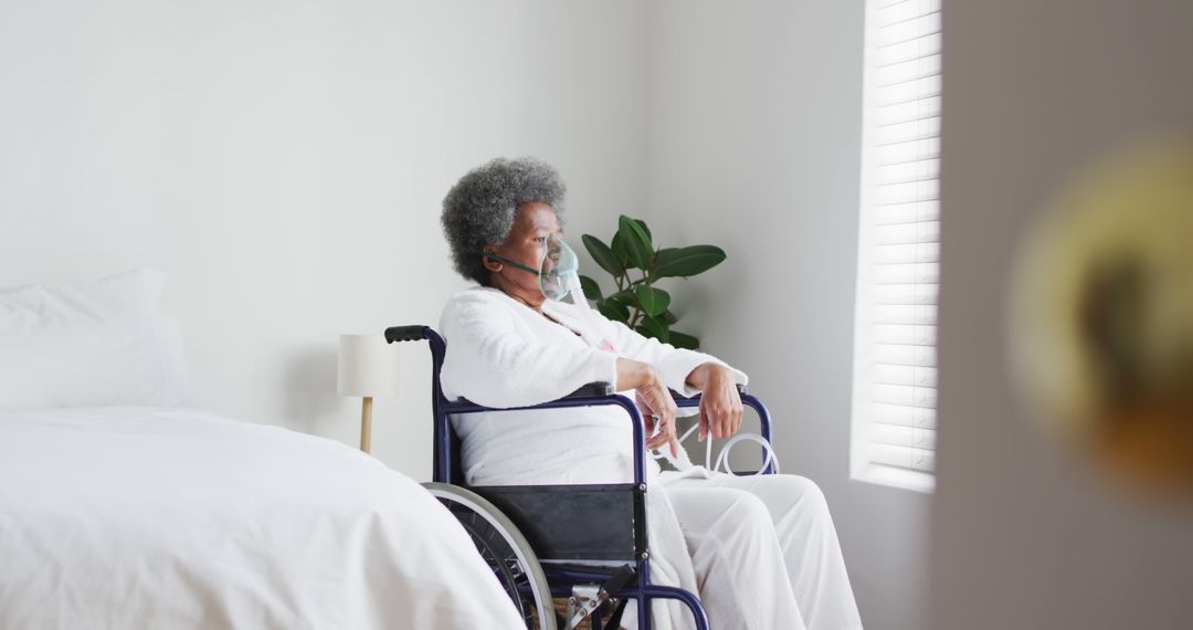 Elderly woman sitting in wheelchair by window wearing mask - Free Images, Stock Photos and Pictures on Pikwizard.com