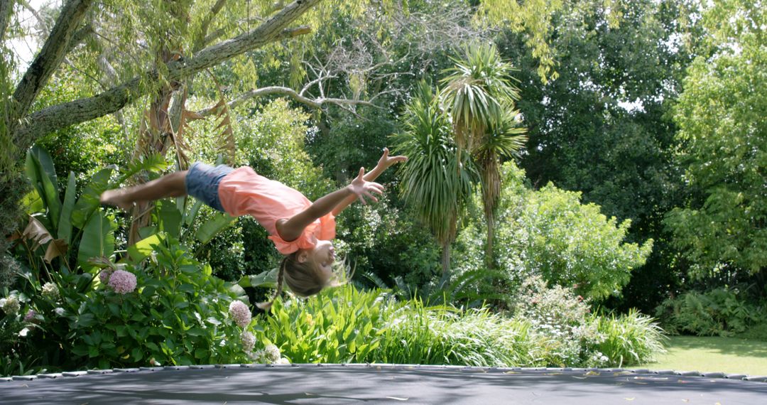 Girl Doing Backflip on Trampoline in Lush Backyard Garden - Free Images, Stock Photos and Pictures on Pikwizard.com