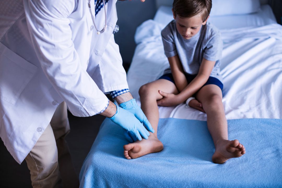 Male Doctor Examining Young Boy's Leg in Hospital Room - Free Images, Stock Photos and Pictures on Pikwizard.com