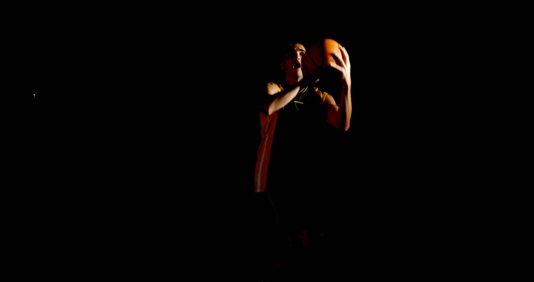 Basketball player preparing to shoot in dark surroundings - Free Images, Stock Photos and Pictures on Pikwizard.com