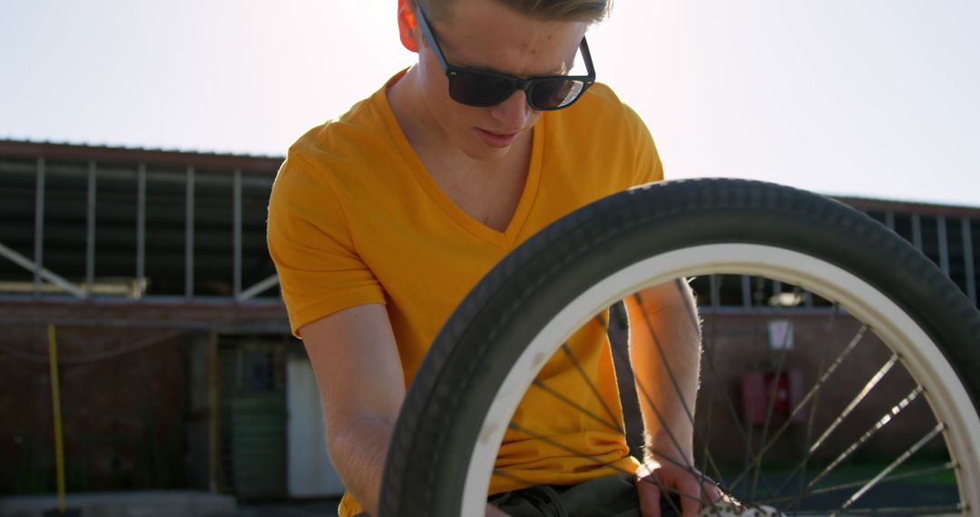 Man Repairing Bicycle Wheel Outdoors in Sunny Day - Free Images, Stock Photos and Pictures on Pikwizard.com