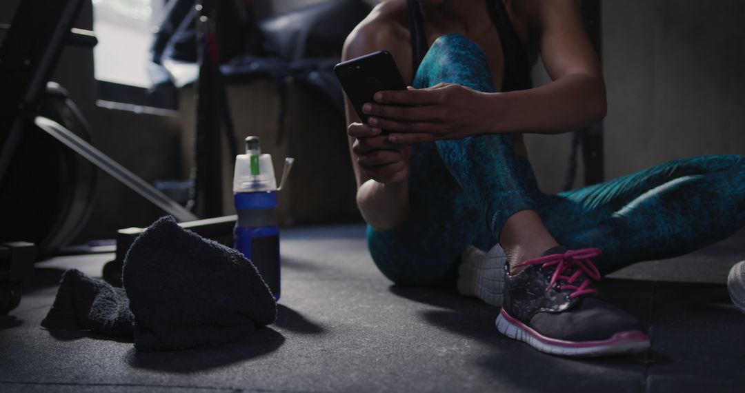 Athletic Woman Taking Break in Gym Using Smartphone