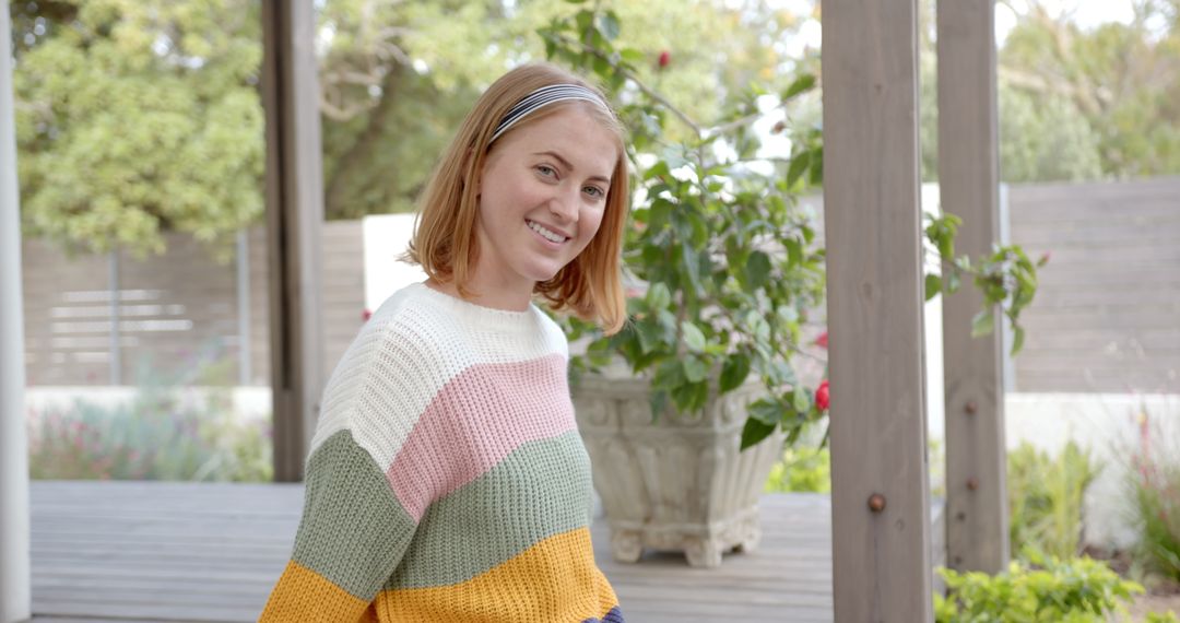 Smiling Woman Enjoying Outdoors in Colorful Knit Sweater on Backyard Deck