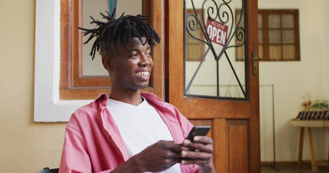Smiling African American Craftsman Using Smartphone in Workshop