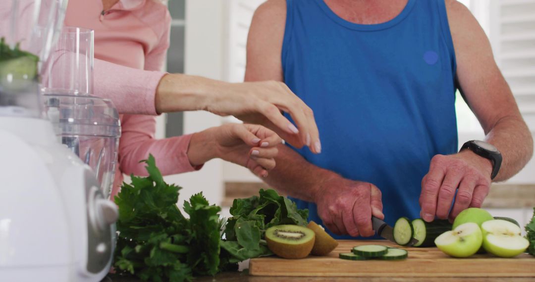 Senior Couple Preparing Fresh Produce Slicing Cucumber and Kiwi on Wooden Board