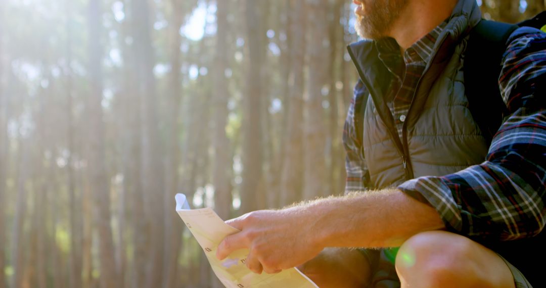 Man reading map in sunny forest during hike - Free Images, Stock Photos and Pictures on Pikwizard.com