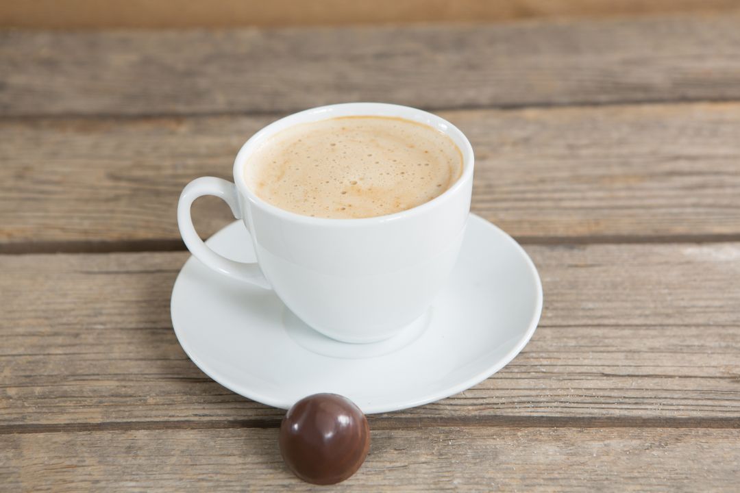 Coffee cup and chocolate ball on wooden surface - Free Images, Stock Photos and Pictures on Pikwizard.com