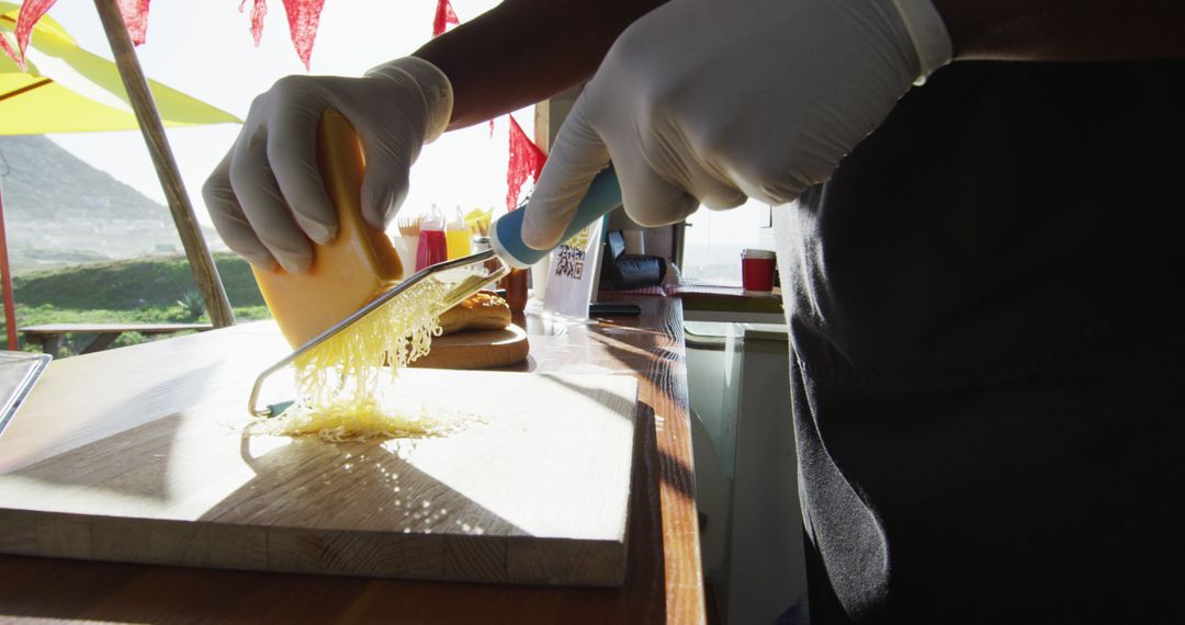 Hands wearing gloves grating cheese in a sunny kitchen - Free Images, Stock Photos and Pictures on Pikwizard.com