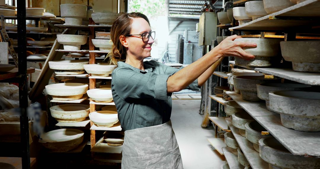 Female Potter Organizing Ceramic Bowls on Shelves in Studio - Free Images, Stock Photos and Pictures on Pikwizard.com