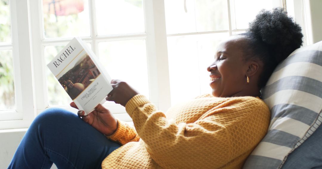 Smiling Woman Reading Book on Couch by Window - Free Images, Stock Photos and Pictures on Pikwizard.com